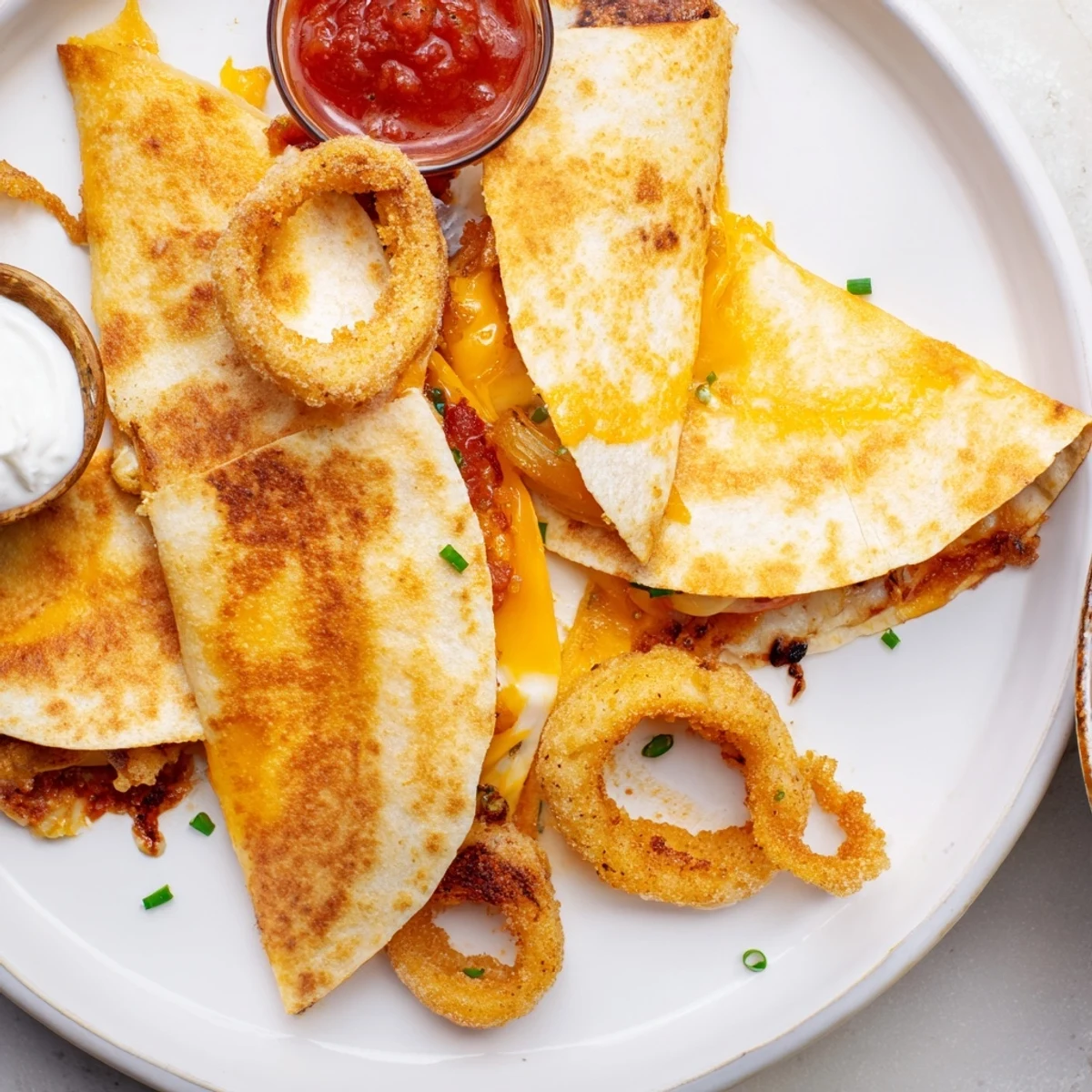 Crispy fried onion rings layered inside cheesy quesadillas sliced into golden triangular wedges