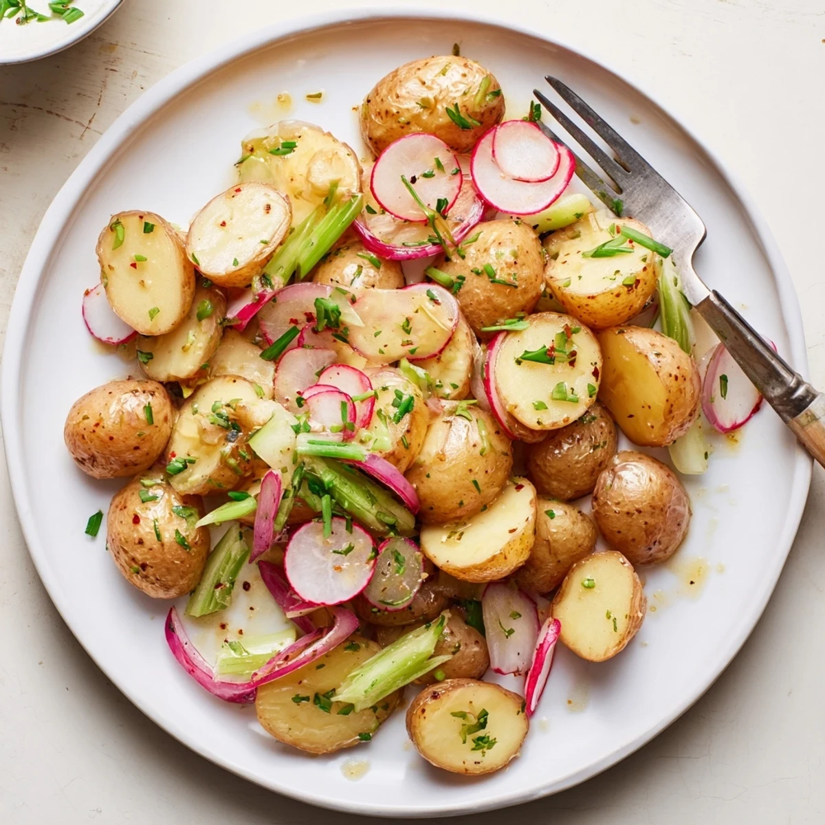 Golden roasted potato salad with crispy potatoes, fresh herbs, and tangy mustard dressing in a serving bowl