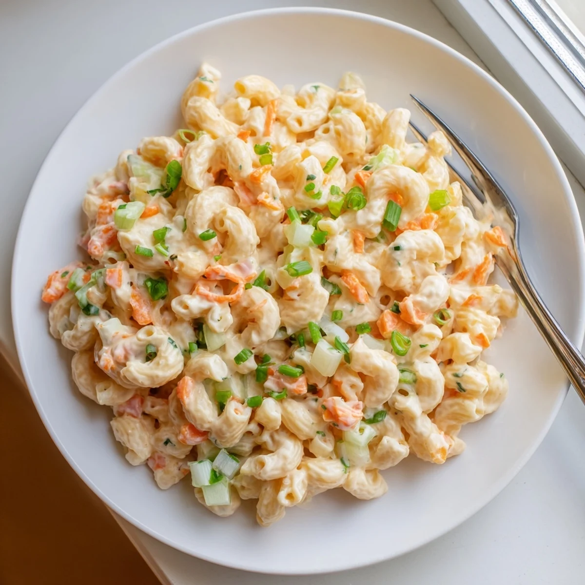 Classic Hawaiian plate lunch side dish showing elbow pasta coated in rich creamy dressing with crisp vegetable mix-ins.