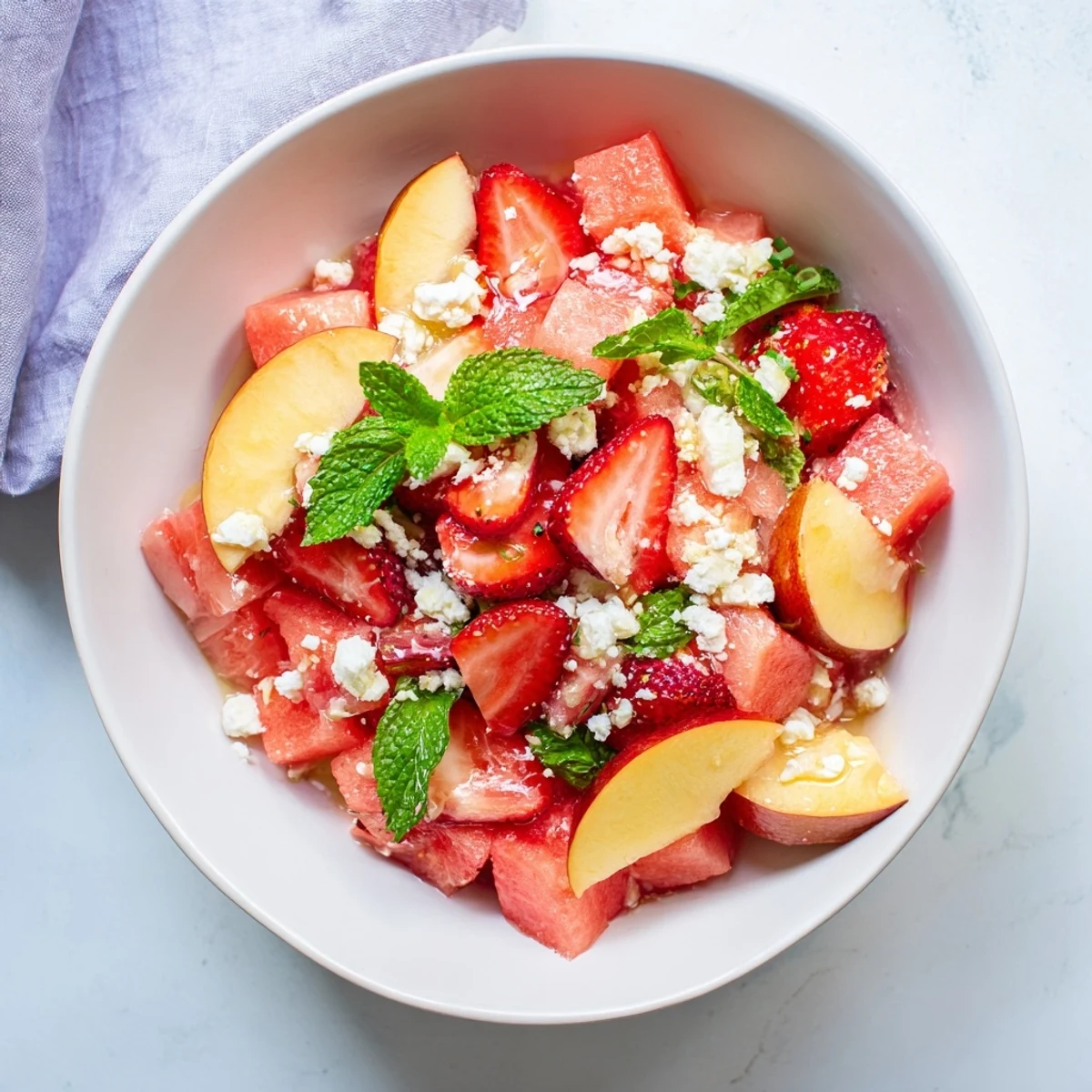 Colorful Summer Peach Watermelon Salad with fresh mint and zesty lime dressing drizzled over juicy fruit