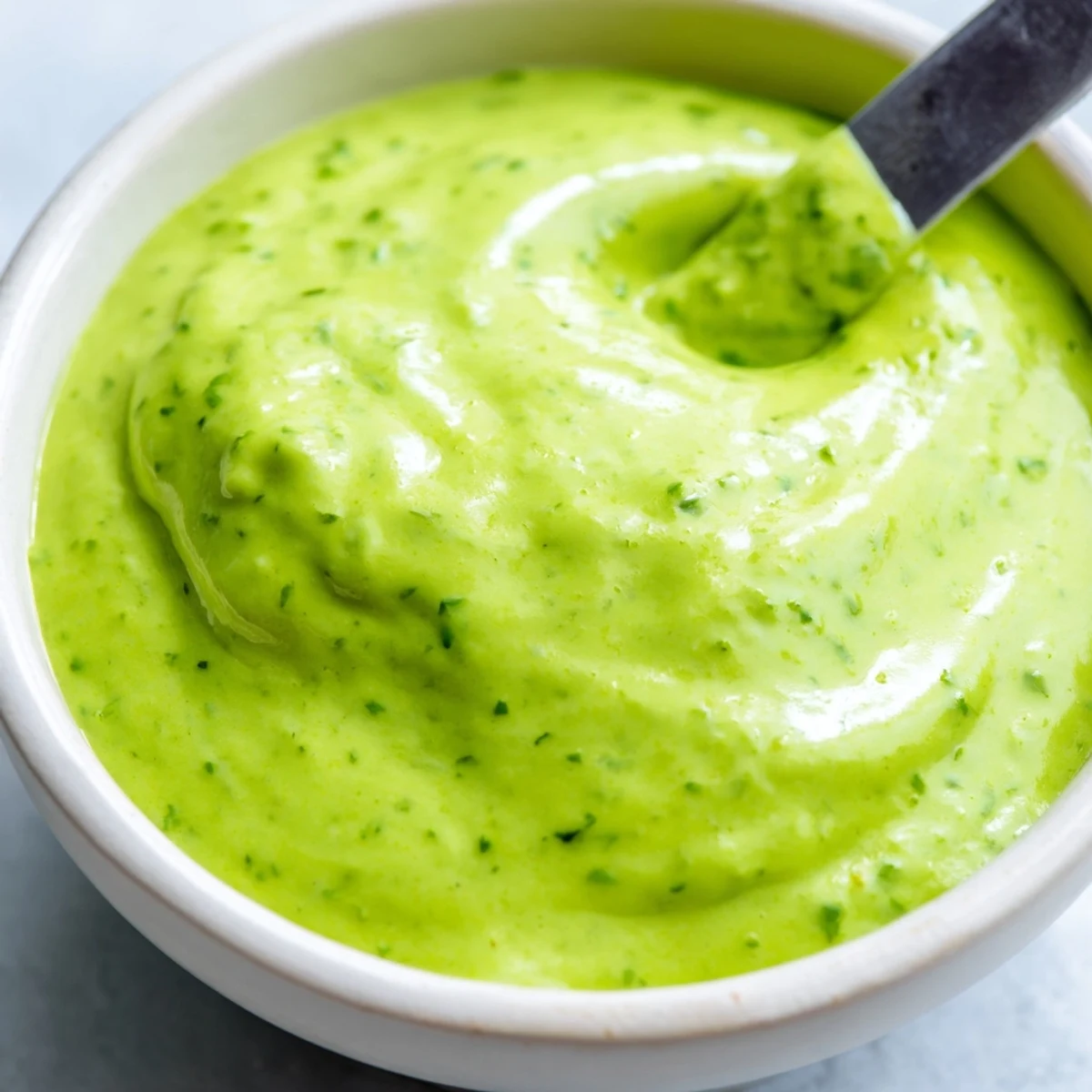Creamy Peruvian green sauce aji verde served in a small white dipping bowl