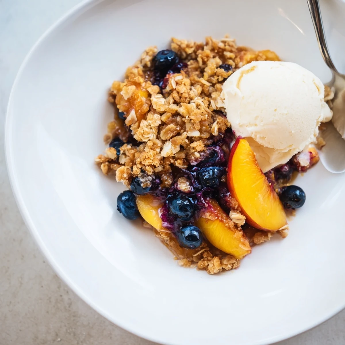 Golden, crisp Blueberry Peach Crumble with bubbling tart-sweet filling and vanilla ice cream