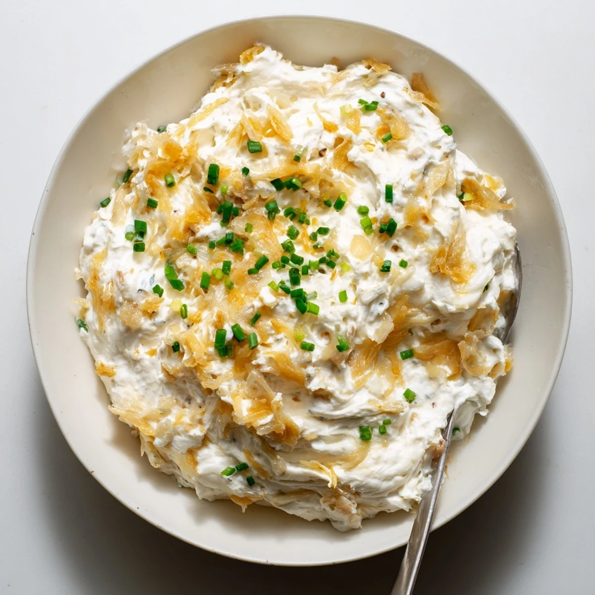 Creamy French onion dip topped with caramelized onions and fresh green onion garnish