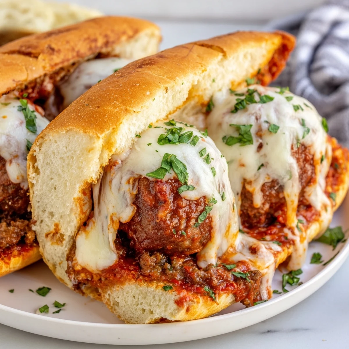 Warm sandwich cross-section revealing sauce-coated meatballs and stretchy melted cheese inside a crispy Italian sub roll