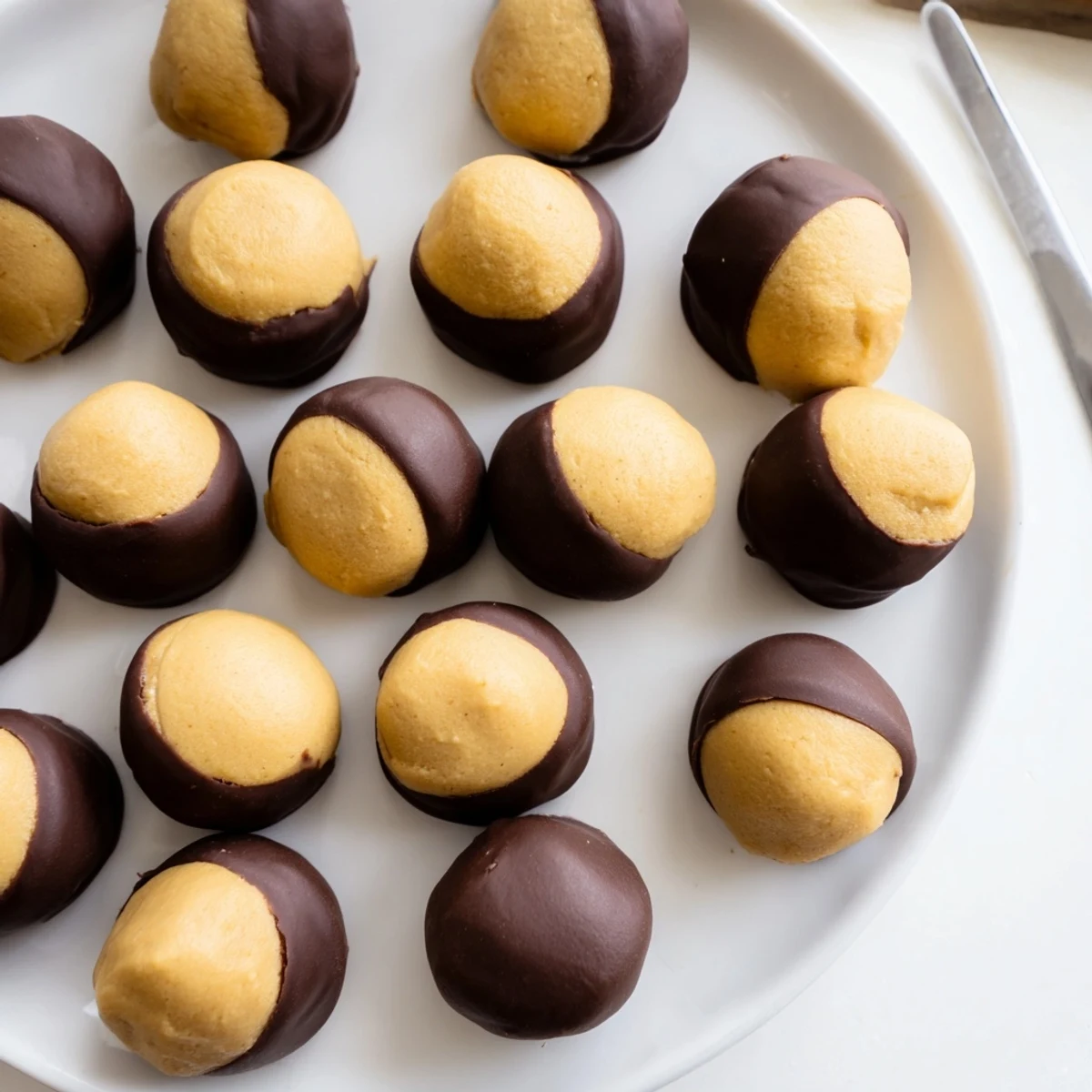 Golden buckeye cookies with glossy chocolate coating on a rustic wooden serving board