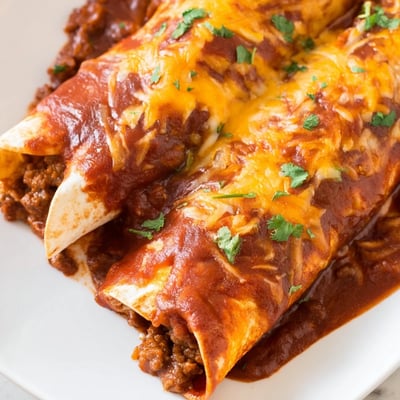 Ground beef filling wrapped in warm corn tortillas, smothered in homemade red sauce and bubbling with savory Tex-Mex spices.