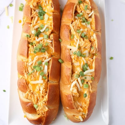 A close-up view of a halved Cheesy Buffalo Chicken Stuffed French Bread filled with spicy chicken and creamy herbs.