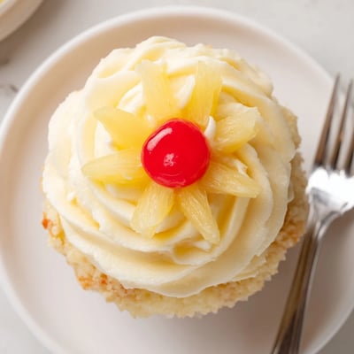 A plate of Dole Whip Cupcakes Recipe served with dried pineapple and cherries